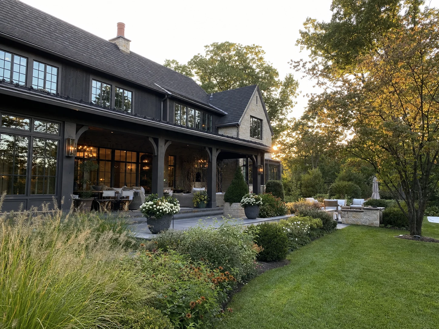 Outdoor-living design concept with a stone terrace, layered planting, and a covered gathering space.
